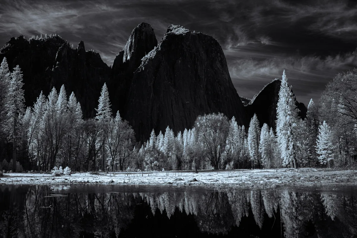 Dark granite formations reflected in still water beneath dramatic clouds
